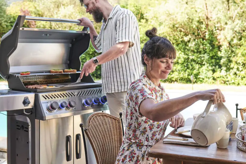 Grillszene im Freien mit Gasgrill und gedecktem Tisch